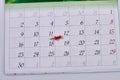 Red push pin lying on a white month calendar.