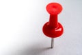 red push pin stuck in white floor. Macro thumbtack top view. Royalty Free Stock Photo