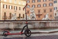 Red push scooters against the backdrop of the Fountain de Neptune on Piazza Navona in the Roma, Italy.