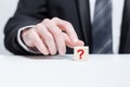Red question mark on wooden block pyramid in businessman hand. FAQ question concept