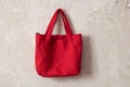 Red quilted bag hanging on white wall on nails