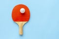 Red racket for table tennis with white ball on blue background. Ping pong sports equipment in minimal style. Flat lay, top view, Royalty Free Stock Photo