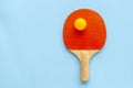 Red racket for table tennis with yellow ball on blue background. Ping pong sports equipment in minimal style. Flat lay, top view, Royalty Free Stock Photo