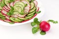 Red radish next to the plate with a spring salad