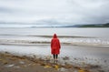 Red raincoat on a tranquil shore Royalty Free Stock Photo