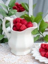 Red raspberries  and green leaves on white laced tablecloth. Royalty Free Stock Photo