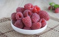 Red raspberries in white plate on gbeige wooden background