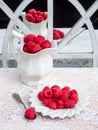 Red raspberries in white plate and pitcher reflecting in old mirror. Royalty Free Stock Photo