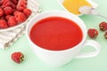 Red raspberry fruit-drink in white cup with paper straw