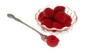 Red raspberry on a small fruit fork with a bowl filled in the background on a white background