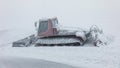 Red ratrak snowcat in winter mountains. A red snow tucker covered with snow.