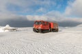 Red ratrak snowcat in winter mountains. A red snow tucker covered with snow.