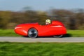 A red recumbent tricycle rushing by on a bikepath