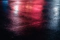 Red reflections of neon light on a street. Dark and rainy evening in the city. Horizontal photo with copy space Royalty Free Stock Photo