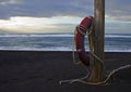 A red rescue circle to rescue people hangs on a wooden pole on the shores of the ocean