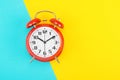 Red retro alarm clock with a big dial, on divided diagonally blue-yellow background