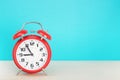 Red retro alarm clock with five minutes to nine o`clock, on wooden table on a blue background Royalty Free Stock Photo