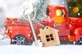 Red retro car with a Christmas tree decorates with the house key in the pickup truck for Christmas. Buying a home, moving,