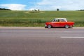 Red retro car is standing on the side of the road near an endless green field Royalty Free Stock Photo