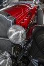 Red retro passenger car with chrome headlights and a radiator grille as a symbol of old engineering Royalty Free Stock Photo