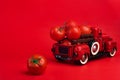 Red retro pickup truck and fresh tomatoes on red background, harvesting, ketchup advertising, creative product presentation