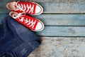 Red retro sneakers and jeans on a blue wooden background Royalty Free Stock Photo