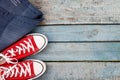 Red retro sneakers and jeans on a blue wooden background Royalty Free Stock Photo