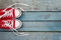 Red retro sneakers with loose braids on a blue wooden background Royalty Free Stock Photo