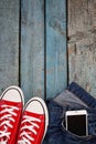 Red retro sneakers and smartphone in a jeans pocket on a blue wo Royalty Free Stock Photo