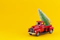 Red retro toy truck with  Christmas tree on truck body on yellow background Royalty Free Stock Photo