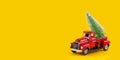 Red retro toy truck with Christmas tree on truck body on yellow background. Long wide banner Royalty Free Stock Photo