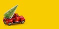 Red retro toy truck with  Christmas tree on truck body on yellow background Royalty Free Stock Photo