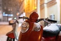 Red retro vintage motor scooter under falling snow parked on winter city street at night Royalty Free Stock Photo