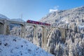 Red Rhaetian railway train on viaduct Langwies, sunshine, winter Royalty Free Stock Photo