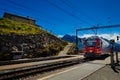 Red RhB train in Alp Grum railway station, Grisons, Switzerland.