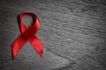 Red ribbon Aids awareness for World HIV/AIDS day on black and white wooden background Royalty Free Stock Photo