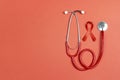 Red ribbon as symbol of aids awareness with stethoscope on red background. 1 december World Aids Day concept