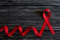 Red ribbon awareness on black wooden table background for World Aids day campaign Royalty Free Stock Photo