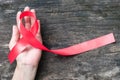 Red ribbon awareness clipping path on woman human hand aged wood background: World aids day campaign to support people living