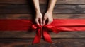 Red ribbon bow with hands on it wooden background