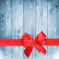 Red ribbon with bow over christmas snow wood background Royalty Free Stock Photo