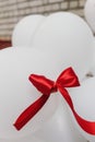 Red ribbon on bunch of white decorative air baloons, balloons we