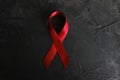 Red ribbon on concrete texture background, symbol of AIDS disease and drug abuse problem