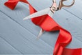 Scissors cutting red ribbon, close-up view on blue Royalty Free Stock Photo