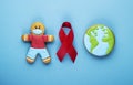 red ribbon and gingerbread boy and planet earth on blue background. world day of fight against cancer Royalty Free Stock Photo