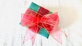 Red ribbon green gift box on white fabric background.
