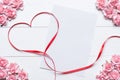 Red ribbon heart symbol with blank paper sheet and pink roses on Royalty Free Stock Photo