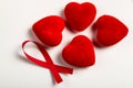 Red ribbon is near the four red heart on the white background/table. World AIDS Day