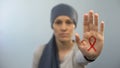 Red ribbon sign on womans palm showing stop gesture, AIDS awareness campaign
