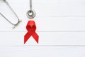 Red ribbon and stethoscope on white wooder background, Symbol of World AIDS Day, Health care concept Royalty Free Stock Photo
